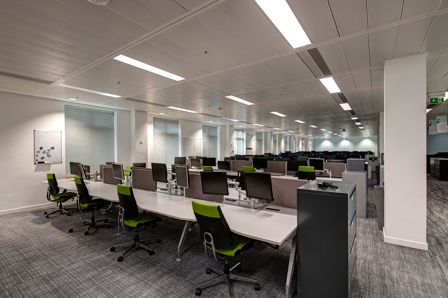 Interior photography of offices by commercial photographers Blink Imaging. You can see rows of desks with chairs and computer screens.